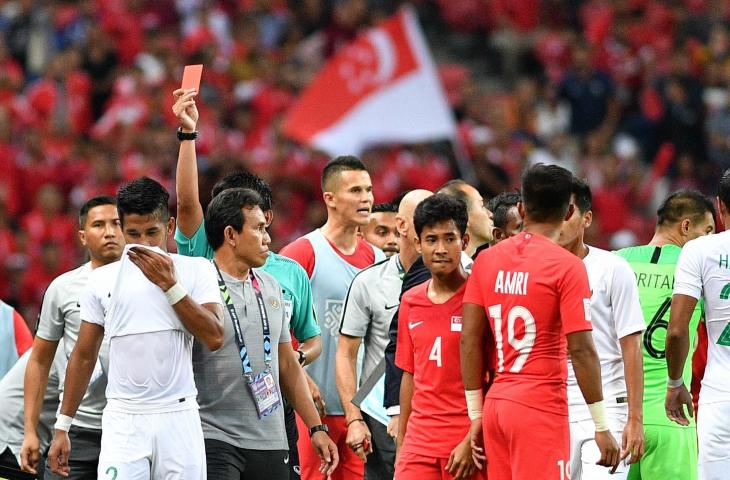 Pemain timnas Indonesia Putu Gede Juni Antara (kedua kiri) meninggalkan lapangan setelah terkena kartu merah saat melawan timnas Singapura dalam penyisihan grub B Piala AFF 2018 di Stadion Nasional Singapura, Jumat (9/11/2018). Indonesia kalah 0-1 dalam pertandingan perdana tersebut. (ANTARA FOTO/Sigid Kurniawan)