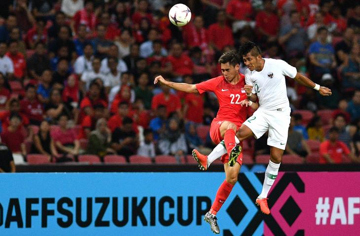 Pemain Timnas Indonesia Putu Gede Juni Antara (kanan) berebut bola di udara dengan pemain timnas Singapura Gabriel Quak Jun Yi dalam penyisihan grub B Piala AFF 2018 di Stadion Nasional Singapura, Jumat (9/11/2018). Indonesia kalah 0-1 dalam pertandingan tersebut. (ANTARA FOTO/Sigid Kurniawan)