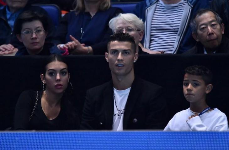 Georgina Rodriguez, Cristiano Ronaldo, dan Cristiano Ronaldo Jr saat menyaksikan laga tenis Novak Djokovic vs ohn Isner pada 12 November 2018. (Glyn Kirk/AFP)