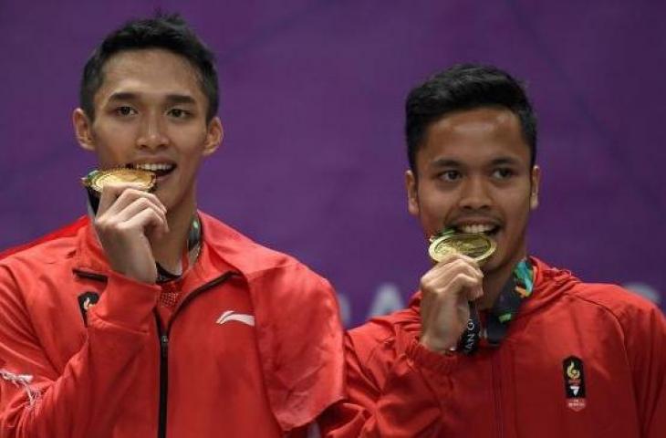 Pebulu tangkis tunggal putra Indonesia peraih medali emas Jonatan Christie (kiri) dan peraih medali perunggu Anthony Sinisuka Ginting (kanan) menggigit medali Asian Games 2018, usai upacara penyerahan medali di Istora Senayan, Jakarta, Selasa (28/8). ANTARA FOTO/INASGOC/Puspa Perwitasari.