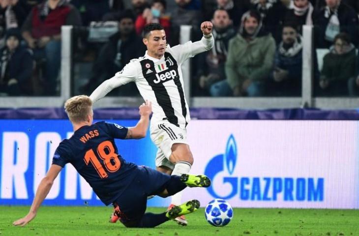 Cristiano Ronaldo menghindari tackle dari pemain Valencia, Daniel Wass di laga Liga Champions pada 27 November 2018 (Migeul Medina/AFP)