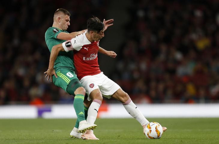 Pemain Vorskla Poltava, Mykhaylo Serhiychuk menghadang pemain Arsenal, Mesut Ozil saat pertandingan grup E Liga Eropa di Emirates Stadium, London (20/9/2018) (AFP)