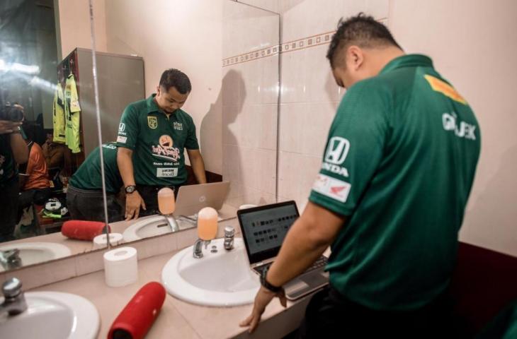 Psikolog Afif Kurniawan sedang memilih lagu yang akan diputar di ruang ganti Persebaya. Tampak dia melakukan hal itu di ruang ganti Stadion Mandala, Jayapura, pada 30 Oktober lalu. (Satrio Wicaksono/Persebaya.id)