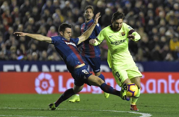 Pemain Levante, Sergio Postigo mencoba merebut bola dari pemain Barcelona, Lionel Messi pada pertandingan La Liga pekan ke-16 (AFP)