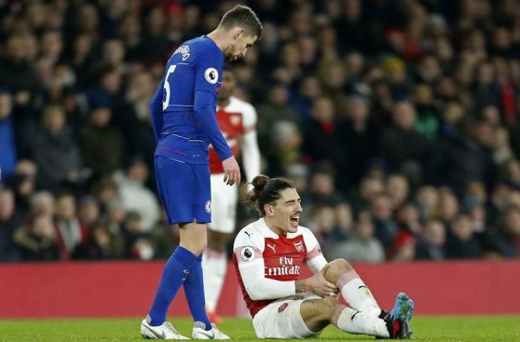 Ekspresi bek Arsenal, Hector Bellerin saat mengalami cedera parah pada lutut kirinya usai berebut bola dengan Marcos Alonso pada laga Arsenal vs Chelsea, Minggu (20/1/2019). [IAN KINGTON / IKIMAGES / AFP]