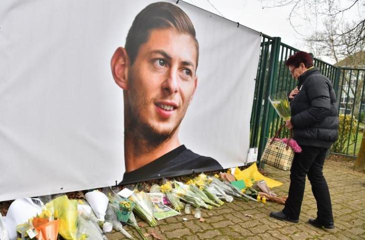 Seorang wanita meletakkan bunga disamping foto Emiliano Sala di pusat pelatih Nantes FC pada 24 Januari 2019. (Loic Venance/AFP)