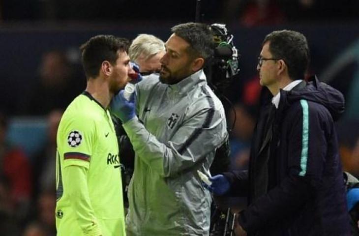 Lionel Messi nampak mendapat perawatan usai diterjang bek Manchester United, Chris Smalling pada pertandingan leg pertama perempatfinal Liga Champions di Old Trafford, Kamis (11/4/2019) dini hari WIB. (OLI SCARFF / AFP)