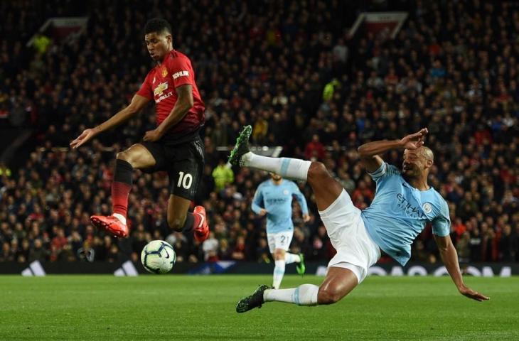 Striker Manchester United, Marcus Rashford, saat berduel dengan bek Manchester City, Vincent Kompany. (Oli Scraff/AFP).