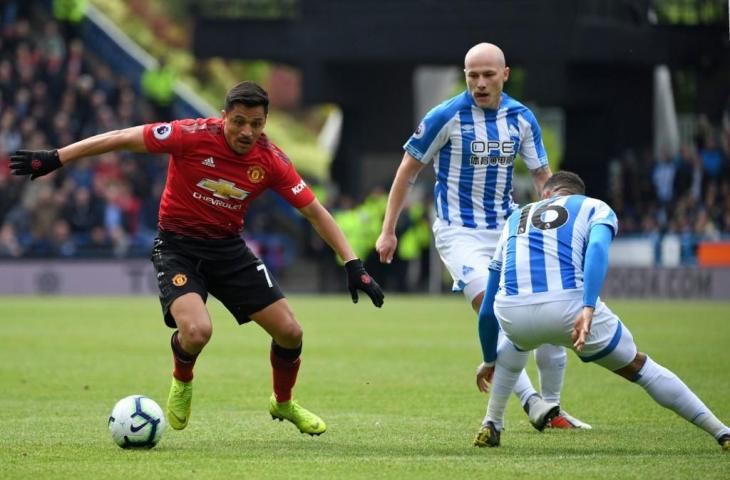 Pemain Manchester United, Alexis Sanchez berusaha menghindar dari kepungan pemain Huddersfield Town. Pada laga pekan ke-37, Manchester United ditahan imbang 1-1, mereka pun gagal tembus empat besar dan Liga Champions musim depan. [PAUL ELLIS / AFP]