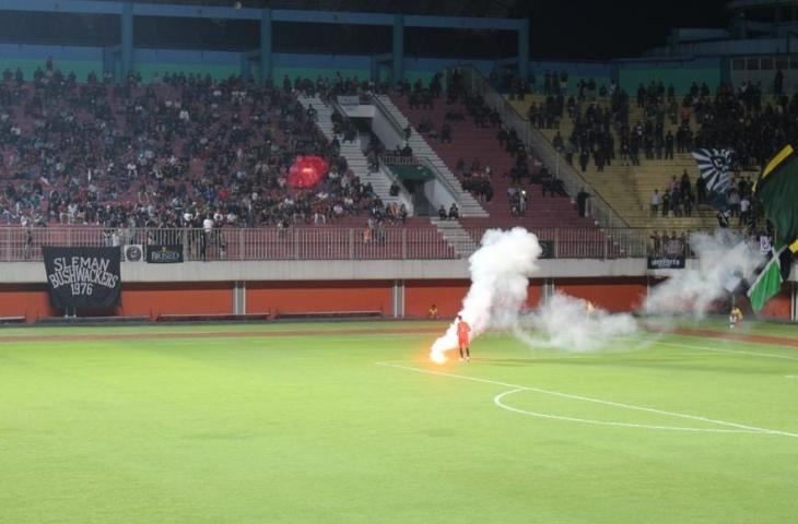 Kiper PSS Sleman, Tri hamdani Guntara, menyingkirkan asap suar yang dilempar suporter ke tengah lapangan saat laga masih berlangsung. (bolatimes.com/M Ilham Baktora)