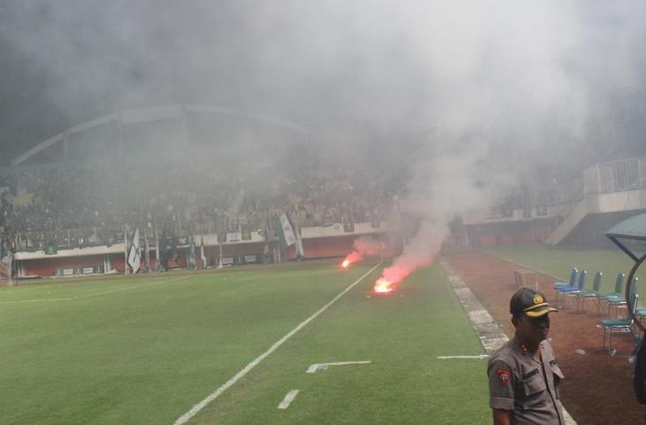 Kepulan asap suar yang sengaja dilempar suporter PSS Sleman ke tengah lapangan saat laga uji coba melawan Persipura Jayapura di Stadion Maguwoharjo, Yogyakarta, Kamis (9/5/2019). (bolatimes.com/M Ilham Baktora)