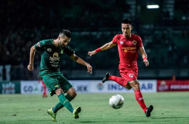 Gelandang serang Persebaya Manuchehr Jalilov dibayang-bayangi bek Kalteng Putra Dendi Agustian Maulana (kanan) pada laga di Stadion Gelora Bung Tomo malam ini (21/5). Performa Persebaya karena hanya bermain imbang 1-1 bakal dievaluasi. (Persebaya.id)