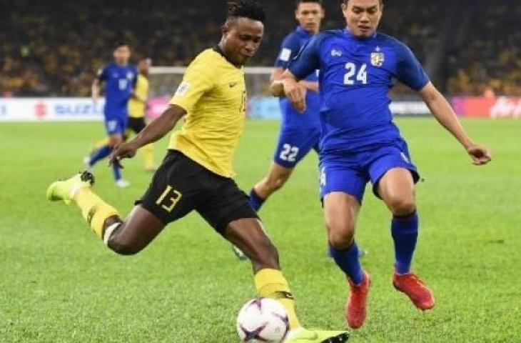 Gelandang Malaysia, Mohamadou Sumareh (kiri), dan bek Thailand Korrakot Wiriyaudomsiri berjuang untuk merebut bola pada pertandingan leg pertama semifinal Piala AFF 2018 di Stadion Nasional Bukit Jalil di Kuala Lumpur pada 1 Desember 2018. (MOHD RASFAN / AFP)