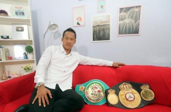 Petinju Indonesia, Daud Yordan, berpose dengan sabuk juara kelas ringan super WBC International Challenge Belt yang belum lama ini didapatnya dan sabuk kelas ringan WBO Inter-Continental, saat berkunjung ke redaksi Suara.com, Kamis (8/8/2019). [Suara.com/Arya Manggala]