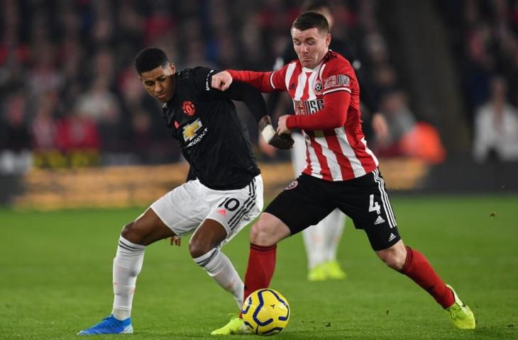 Penyerang Manchester United, Marcus Rashford berebut bola dengan pemain Sheffield, John Fleck. Pada laga lanjutan Liga Primer Inggris yang berlangsung, Minggu (24/11/2019) tersebut kedua tim bermain sama kuat 3-3. [PAUL ELLIS / AFP]