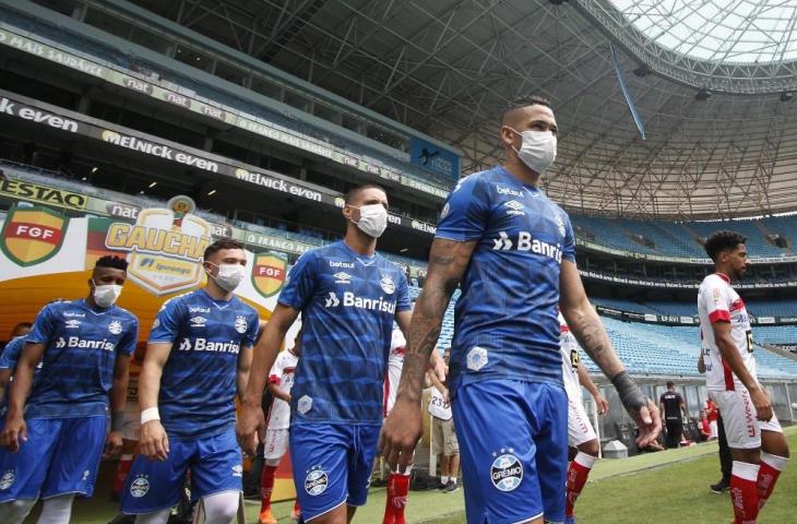 Para pemain Gremio masuk lapangan menggunakan masker. (Richard Ducker/AFP).