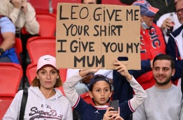 Fan cilik minta jersey Lionel Messi saat PSG melawan RB Leipzig di Liga Champions, Rabu (20/10/2021). (FRANCK FIFE / AFP)