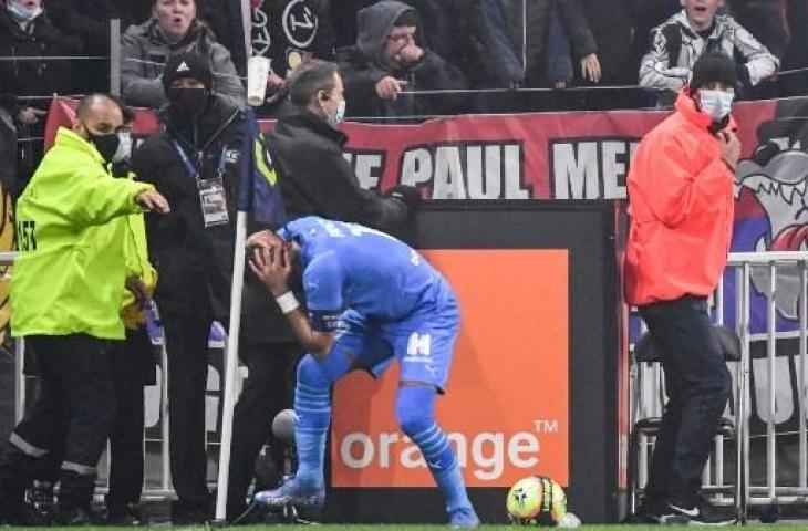 Dimitri Payet berbaring di lapangan setelah kepalanya terkenal botol yang dilemparkan dari tribun saat pertandingan Ligue 1 Prancis antara Lyon vs Marseille. (PHILIPPE DESMAZES / AFP)