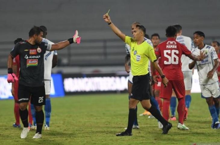 Wasit Fariq Hitaba (ketiga kanan) memberikan kartu kuning kepada penjaga gawang Persija Jakarta Andritany (kiri) setelah terlibat keributan dengan pemain Persib Bandung dalam pertandingan sepak bola Liga 1 di Stadion I Wayan Dipta, Gianyar, Bali, Selasa (1/3/2022). Persib Bandung memenangkan pertandingan dengan skor 2-0. ANTARA FOTO/Nyoman Budhiana/rwa