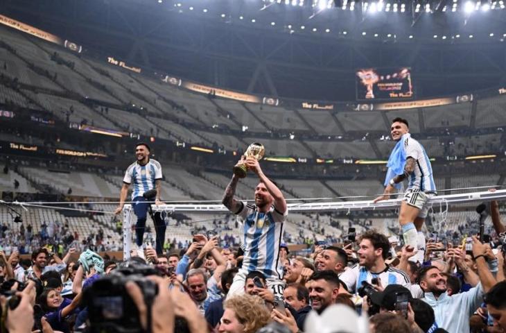 Penyerang Argentina, Lionel Messi, mengangkat Trofi Piala Dunia 2022 bersama pendukung usai mengalahkan Prancis di Stadion Lusail di Lusail, utara Doha pada 18 Desember 2022. (AFP/Kirill Kudryavtsev)