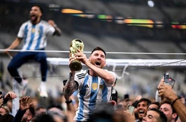 Penyerang Argentina, Lionel Messi, mengangkat Trofi Piala Dunia 2022 bersama pendukung usai mengalahkan Prancis di Stadion Lusail di Lusail, utara Doha pada 18 Desember 2022. (AFP)