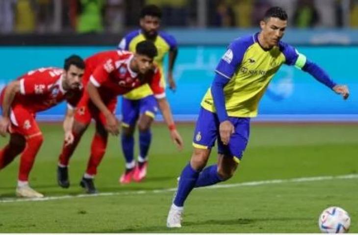 Penyerang Al Nassr asal Portugal, Cristiano Ronaldo (kanan) melepaskan tembakkan untuk mencetak gol ketiga timnya dari penalti selama pertandingan Liga Arab Saudi antara Al-Wehda vs Al-Nassr di Stadion King Abdulaziz di Mekkah pada Jumat (10/2/2023) dini hari WIB. (AFP)