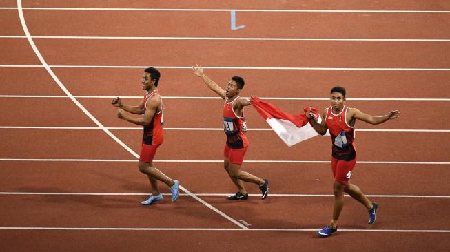 Selebrasi tiga dari empat pelari Indonesia, Lalu Muhammad Zohri (kiri), Fadlin (tengah) dan Eko Rimbawan, membawa bendera Merah Putih usai meraih medali perak nomor estafet 4x100 meter putra, pada Asian Games 2018 di Stadion Utama Gelora Bung Karno, Senayan, Jakarta, Kamis (30/8). [Antara/INASGOC/Dwi Oblo]