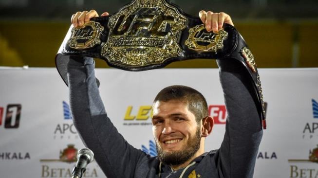 Juara dunia kelas ringan UFC, Khabib Nurmagomedov, memamerkan sabuk juaranya setibanya di Makhachkala, Rusia, Senin (8/10/2018). [AFP/Vasily Maximov]