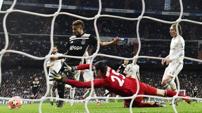 Pemain depan Ajax David Neres mencetak gol setelah melewati kiper Real Madrid Thibaut Courtois pada pertandingan leg kedua babak 16 besar Liga Champions antara Real Madrid melawan Ajax Amsterdam di Stadion Santiago Bernabeu, Madrid, Rabu (6/3) dini hari WIB. [JAVIER SORIANO / AFP]