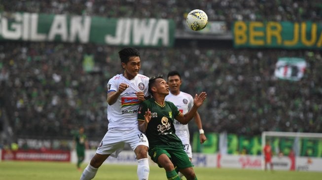 Pesepak bola Persebaya Surabaya Irfan Jaya (kanan) berebut bola di udara dengan pesepak bola Arema FC Jayus Hariono pada laga final leg 1 Piala Presiden 2019 di Gelora Bung Tomo, Surabaya, Jawa Timur, Selasa (9/4/2019). Pertandingan tersebut berakhir imbang dengan skor 2-2. ANTARA FOTO/Zabur Karuru