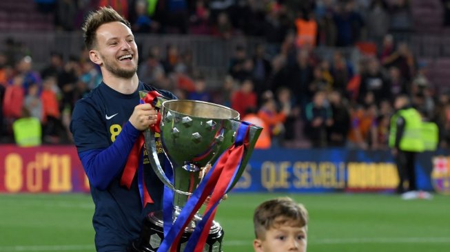 Gelandang Barcelona, Ivan Rakitic memegang trofi juara Liga Spanyol usai timnya keluar sebagai kampiun di musim 2018/19. [LLUIS GENE / AFP]