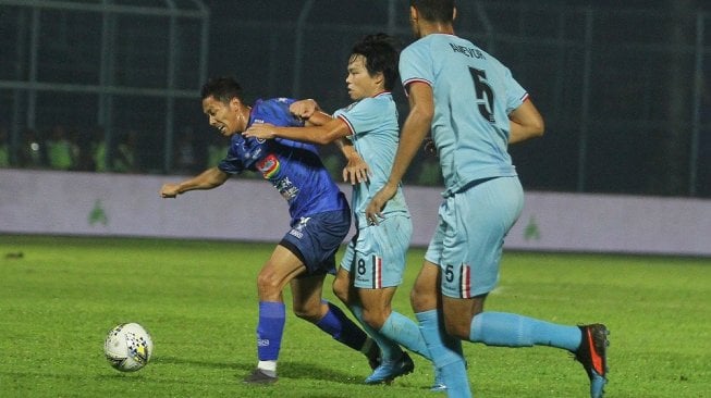 Pesepak bola Arema FC, Dendy Santosa (kiri) berusaha melepaskan diri dari hadangan pesepakbola Persela Lamongan, Kei Hirose (tengah) dan Mawouna Kodjo (kanan) dalam pertandingan Liga 1 di Stadion Kanjuruhan, Malang, Jawa Timur, Senin (27/5/2019). Di akhir babak pertama, Arema FC sementara unggul dengan skor 3-2. ANTARA FOTO/Ari Bowo Sucipto