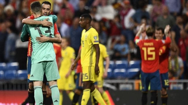 Gelandang Timnas Spanyol, Sergio Busquets, berpelukan dengan penjaga gawang Kepa Arrizabalaga setelah negaranya menang 3-0 atas Swedia pada laga Kualifikasi Piala Eropa 2020 Grup F di Santiago Bernabeu, Madrid, Senin (10/6/2019). [AFP/Oscar Del Pozo]