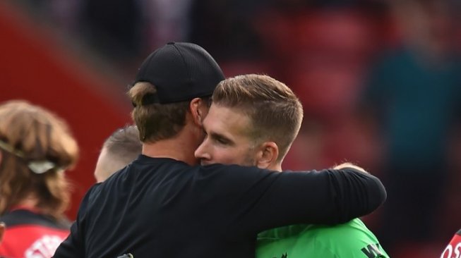 Kiper Liverpool, Adrian San Miguel berpelukan dengan Jurgen Klopp setelah laga antara Southampton vs Liverpool di Stadion St Mary's, Sabtu (17/8.2019). (GLYN KIRK / AFP)