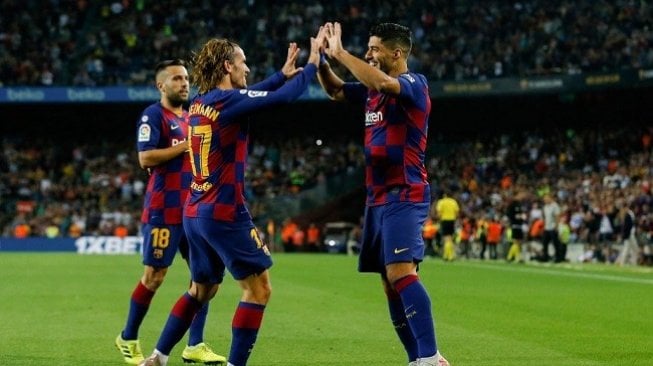 Stiker Barcelona Luis Suarez merayakan gol bersama Antoine Griezmann ke gawang Valencia di laga lanjutan Liga Spanyol yang dihelat di Stadion Camp Nou, Minggu (15/9/2019) dini hari WIB. (AFP)