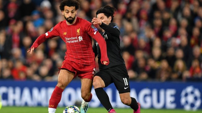 Winger Liverpool, Mohamed Salah (kiri) berduel dengan winger RB Salzburg, Takumi Minamino dalam laga Liga Champions 2019/2020 di Anfield, Kamis (3/10/2019) dini hari WIB. [Paul ELLIS / AFP]