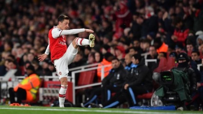 Pemain Arsenal Mesut Ozil melakukan pemanasan ketika hendak memasuki lapangan pertandingan, Minggu (15/12/2019). [AFP]