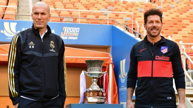 Pelatih Real Madrid, Zinedine Zidane (kiri) dan pelatih Atletico Madrid, Diego Simeone berpose di sebelah trofi Piala Super Spanyol jelang laga final di King Abdullah Sports City, Jeddah, Arab Saudi. [Giuseppe CACACE / AFP]