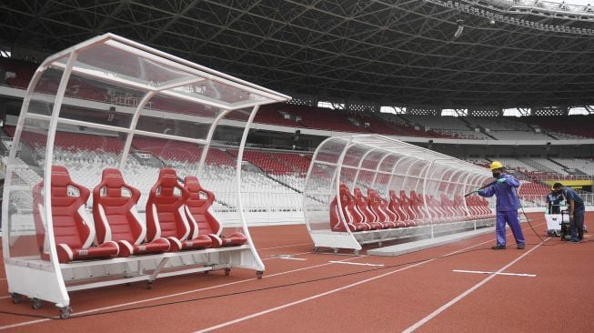 Petugas menyemprotkan cairan disinfektan ke bangku pemain di Kompleks Stadion Utama Gelora Bung Karno (SUGBK), Senayan, Jakarta, Kamis (26/3).  [ANTARA FOTO/Puspa Perwitasari]