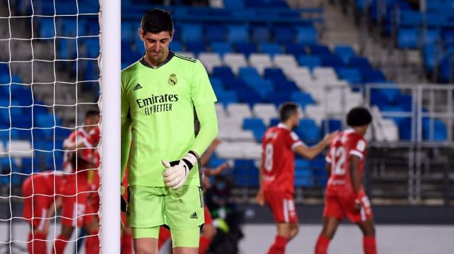 Reaksi kiper Real Madrid Thibaut Courtois usai kebobolan via tendangan penalti yang dieksekusi gelandang Sevilla Ivan Rakitic dalam laga pekan ke-35 Liga Spanyol, di Estadio Alfredo Di Stefano, Senin (10/5/2021) dini hari WIB. [PIERRE-PHILIPPE MARCOU / AFP].