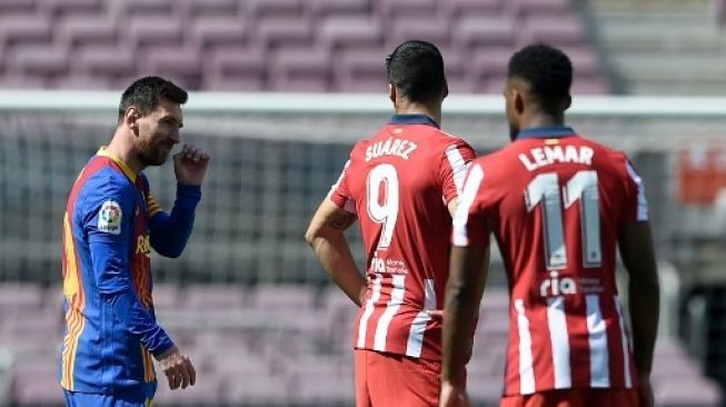 Lionel Messi berbicara dengan Luis Suarez (tengah) di tengah pertandingan La Liga antara Barcelona vs Atletico di Camp Nou, 8 Mei 2021. [AFP]