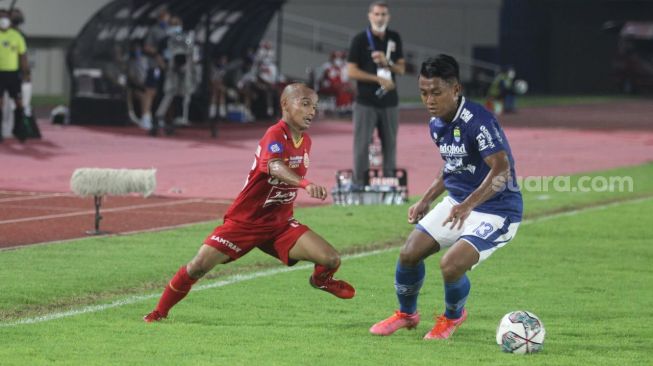 Winger Persija Jakarta, Riko Simanjuntak berebut bola dengan pemain Persib Bandung Febri Hariyadi di laga pekan ke-12 BRI Liga 1 2021/2022 di Stadion Manahan, Solo, Sabtu (20/11/2021). [Suara.com/Ronald Seger Prabowo].