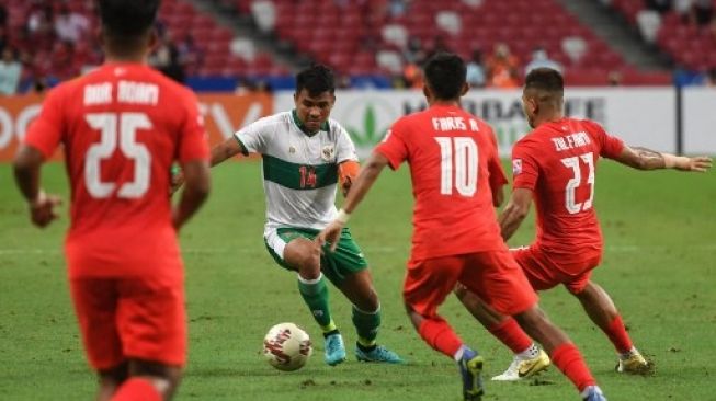 Asnawi Mangkualam Bahar (kedua dari kiri) mencoba melewati pemain Singapura Faris Ramli (kedua dari kanan) dan Zulfahmi Arifin (kanan) pada leg pertama semifinal Piala AFF 2020 antara Singapura dan Indonesia di Stadion Nasional di Singapura pada 22 Desember 2021. Roslan RAHMAN / AFP